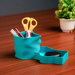 Turquoise desk organizer with scissors, pen, and black object on a wooden surface.