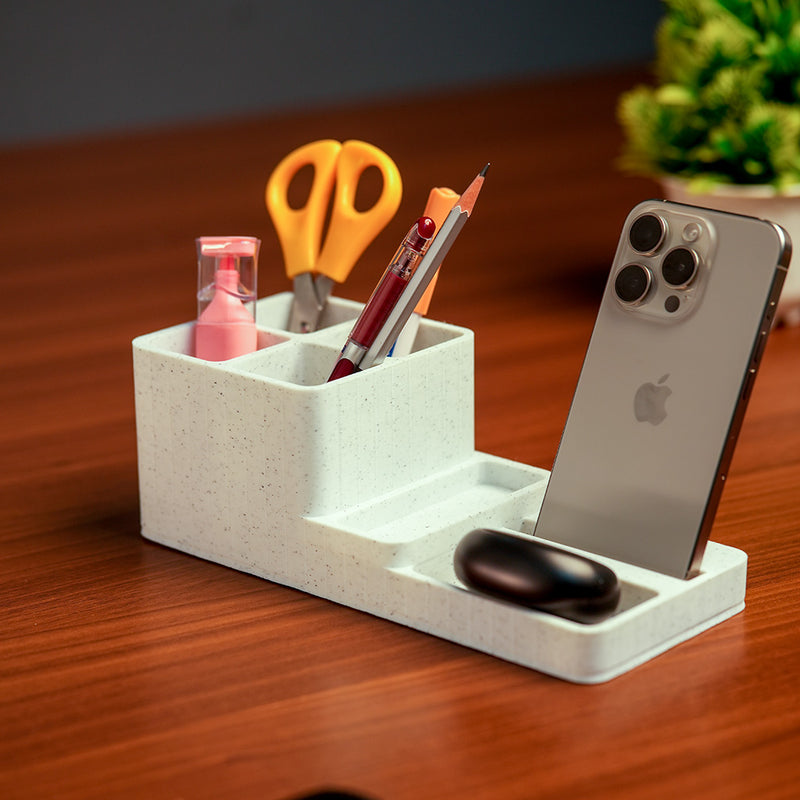 White desk organizer with phone stand, pens, scissors, and other items on a wooden surface.