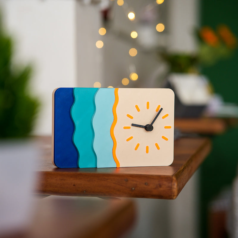 Colorful clock with wavy design on a wooden surface, blurred indoor background