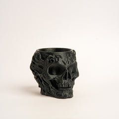 Black skull-shaped candle holder on a light beige background