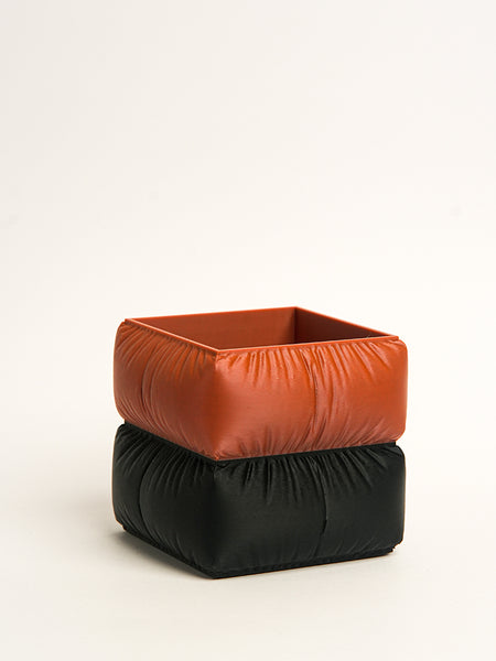 Two stacked fabric containers, one orange and one black, on a white background