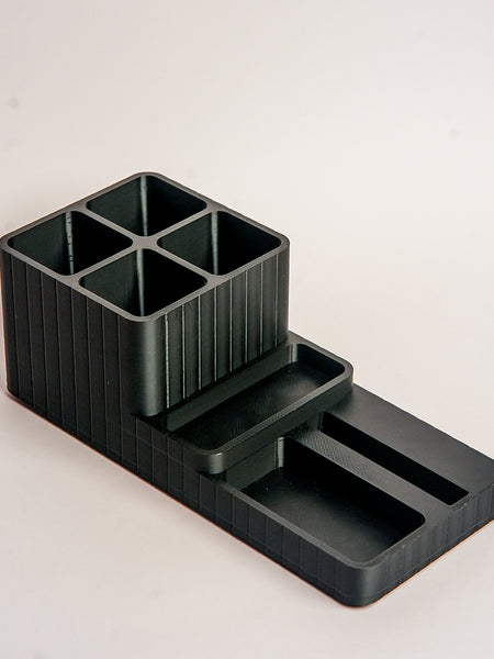 Black plastic desk organizer with compartments on a light gray background