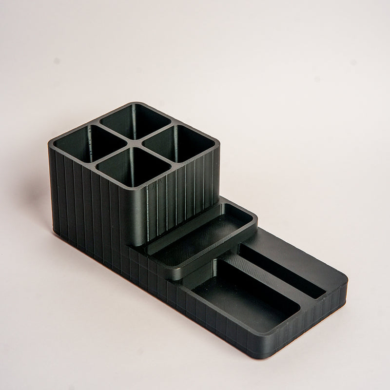 Black plastic desk organizer with compartments on a light gray background