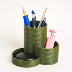 Green multi-compartment desk organizer with stationery items on a white background