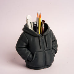 Black hoodie-shaped pen holder with stationery items on a light pink background