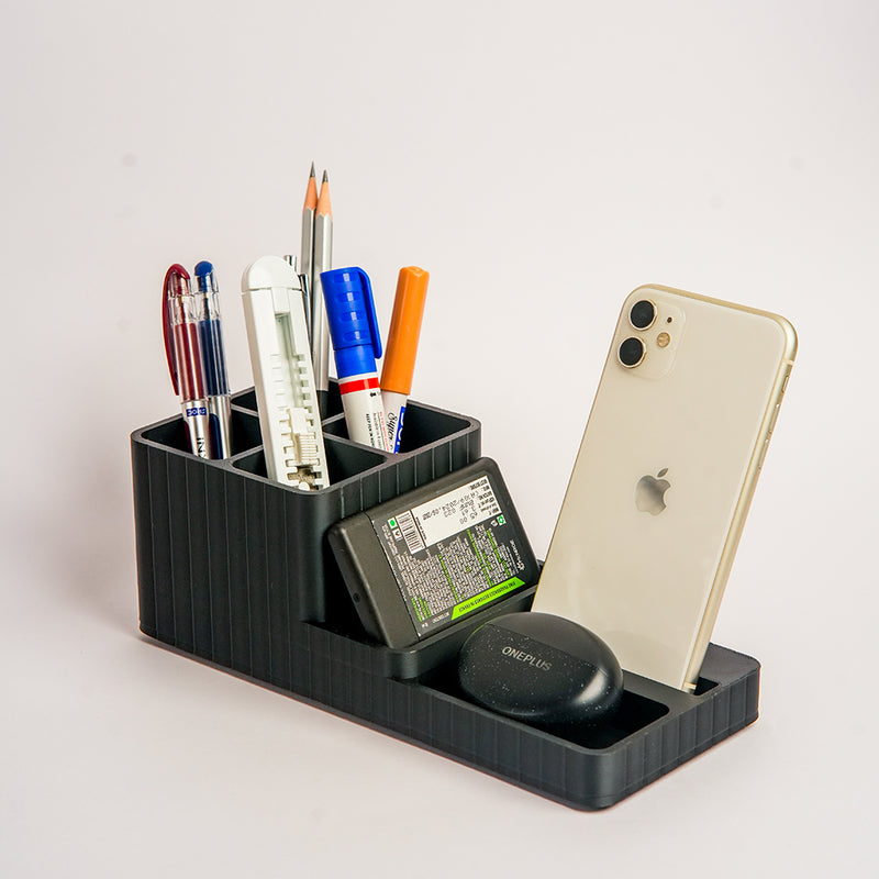 Black desk organizer with stationery items and a phone on a light gray background