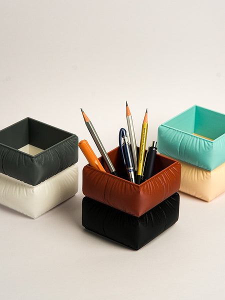 Set of colorful square-shaped pencil holders with pens on a light background in Sofa shape
