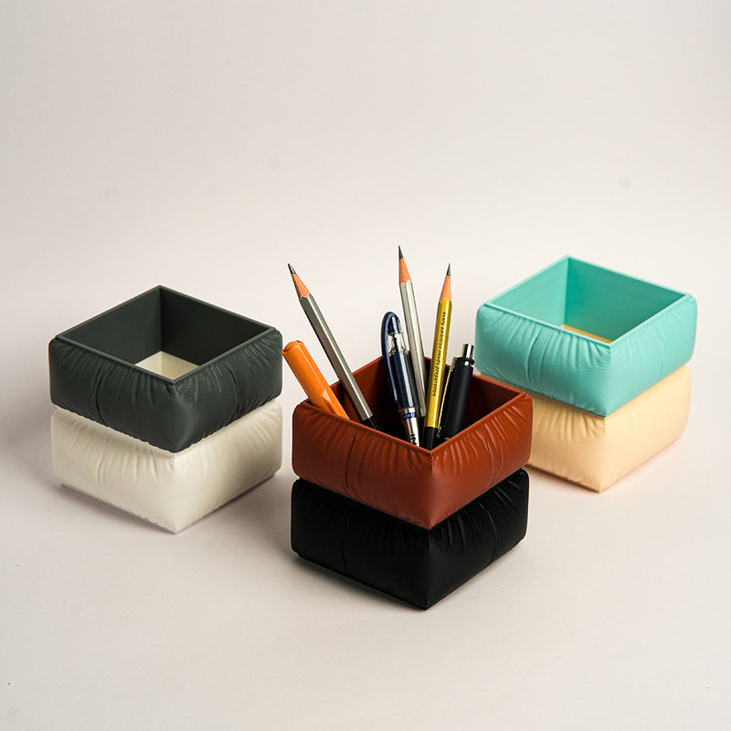 Set of colorful square-shaped pencil holders with pens on a light background in Sofa shape
