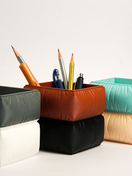 Colorful geometric pencil holders with pens on a white background