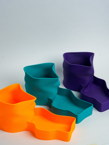 Turquoise desk organizer with scissors, pen, and black object on a wooden surface.