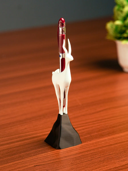 Deer-shaped pen holder with a red pen on a wooden surface