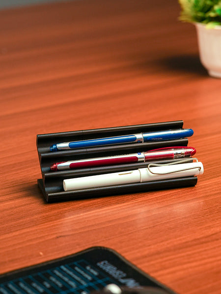 Wooden pen holder with three pens on a beige background