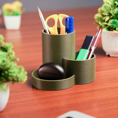 Green cylindrical desk organizer with stationery items on a wooden surface