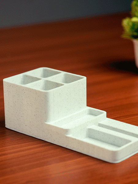 White desk organizer with stationery items and a phone on a light gray 