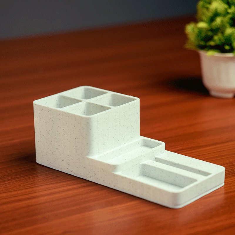 White desk organizer with stationery items and a phone on a light gray 